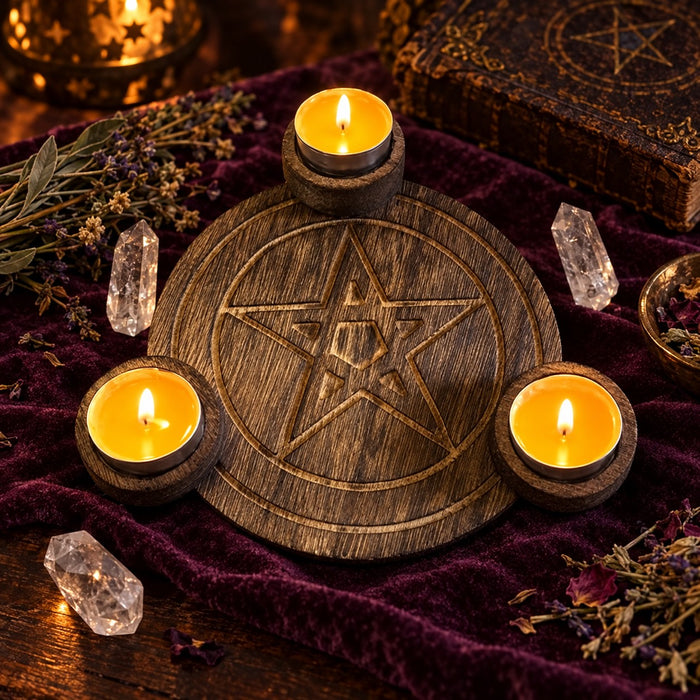 Carved wooden pentagram altar candle holder with three lit tealights on plum velvet, surrounded by quartz crystals and dried herbs